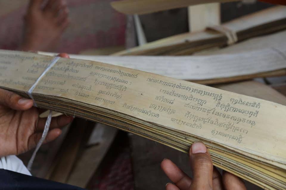 បុរសម្នាក់បង្រៀនយុវជនខ្មែរឱ្យចេះជំនាញចារសាស្ត្រាស្លឹករឹតនៅក្នុងតំបន់រមណីយដ្ឋានអង្គរ