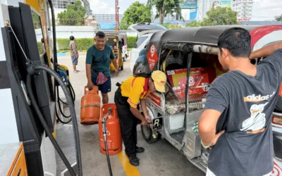 An employee (C) pumps liquefied petroleum gas (LPG) into the vehicle of a customer at a fuel station in Phnom Penh on March 23, 2026. A major energy supplier in Cambodia has said it will halt sales of liquefied petroleum gas from the start of next month due to supply disruptions resulting from the Middle East war. (Photo by TANG CHHIN Sothy / AFP)